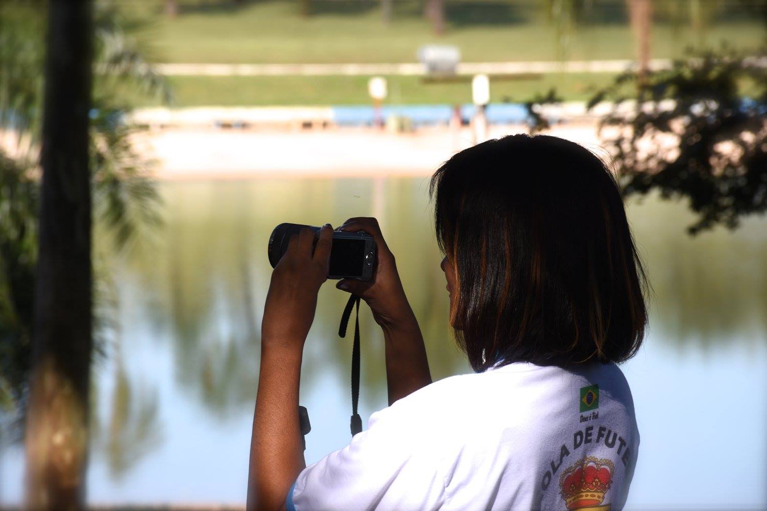 Aluna fotografando à beira do lago